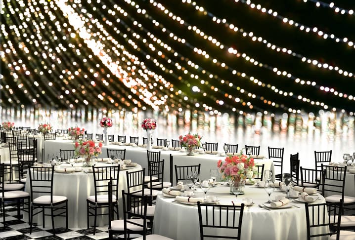 Elegant event with round tables, floral centerpieces, and string lights in Yonkers, NY