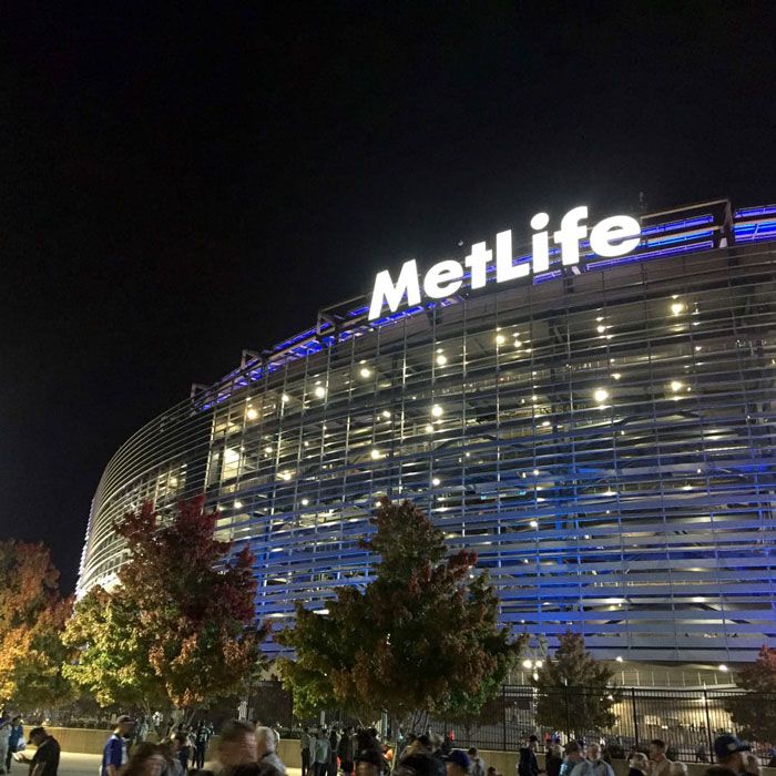 MetLife Stadium exterior at night with illuminated facade and crowd outside in Newyork